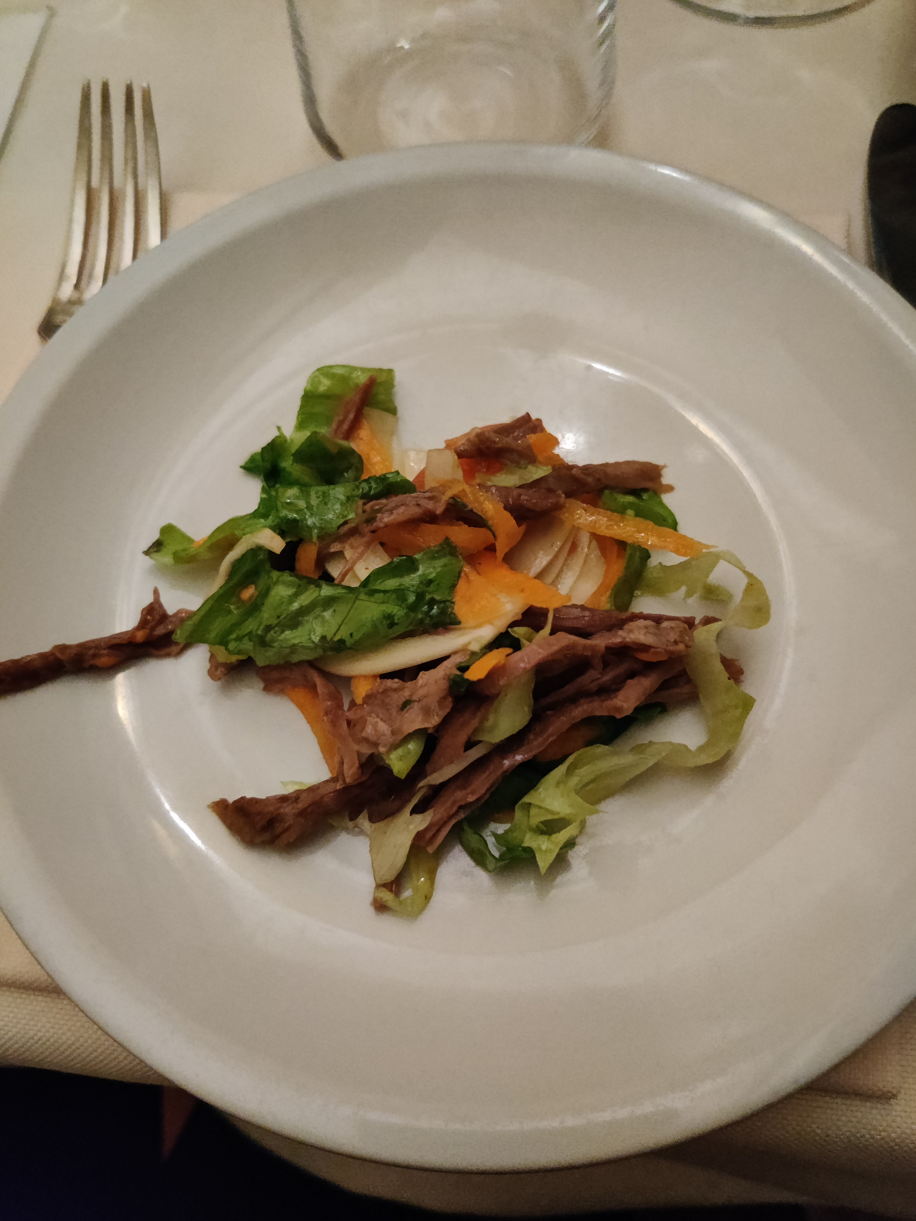 Starter of thinly sliced braised meat with mixed salad leaves and colourful roasted vegetables