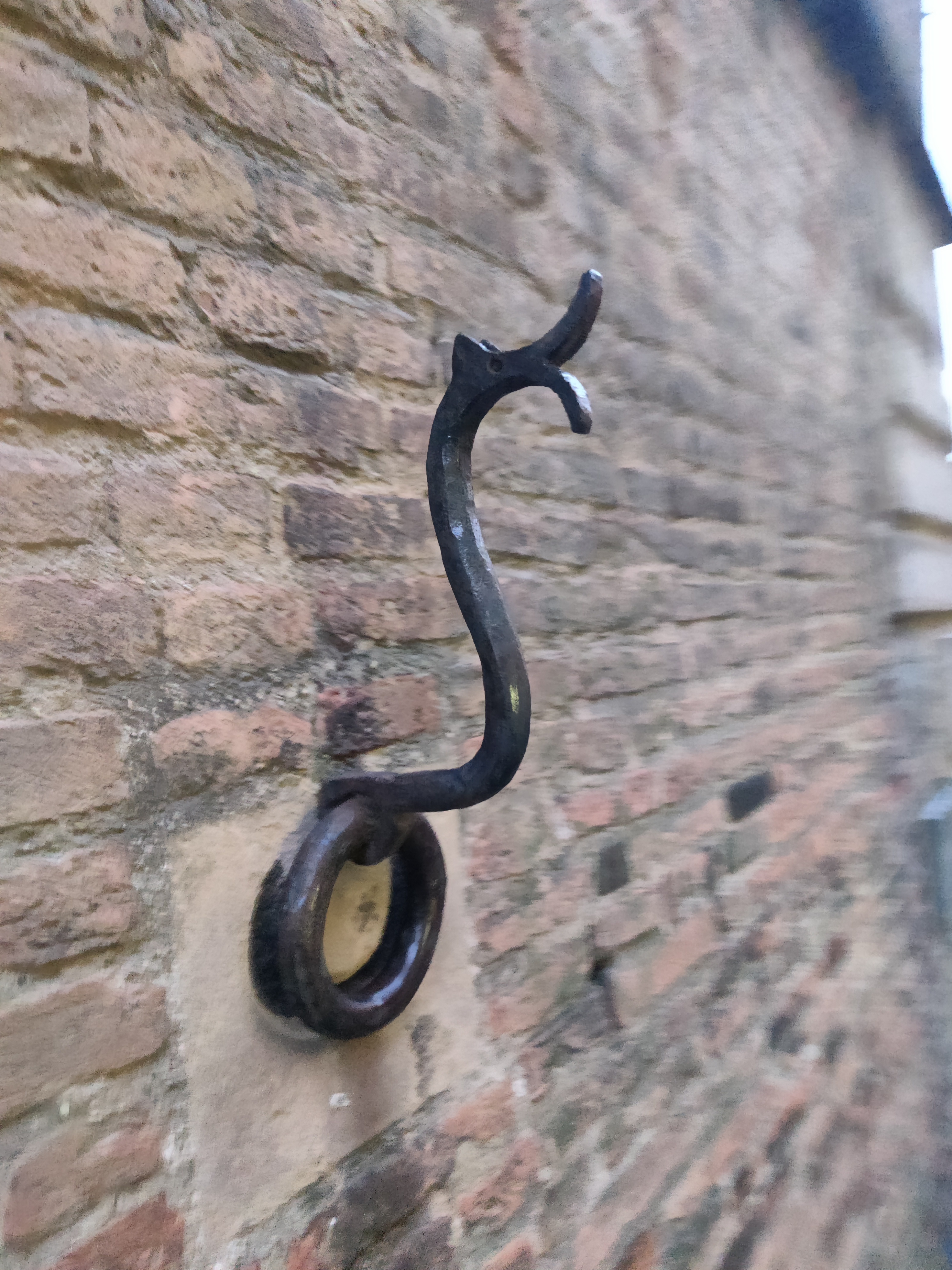 Ornate medieval iron hook and ring fixed into an ancient brick wall
