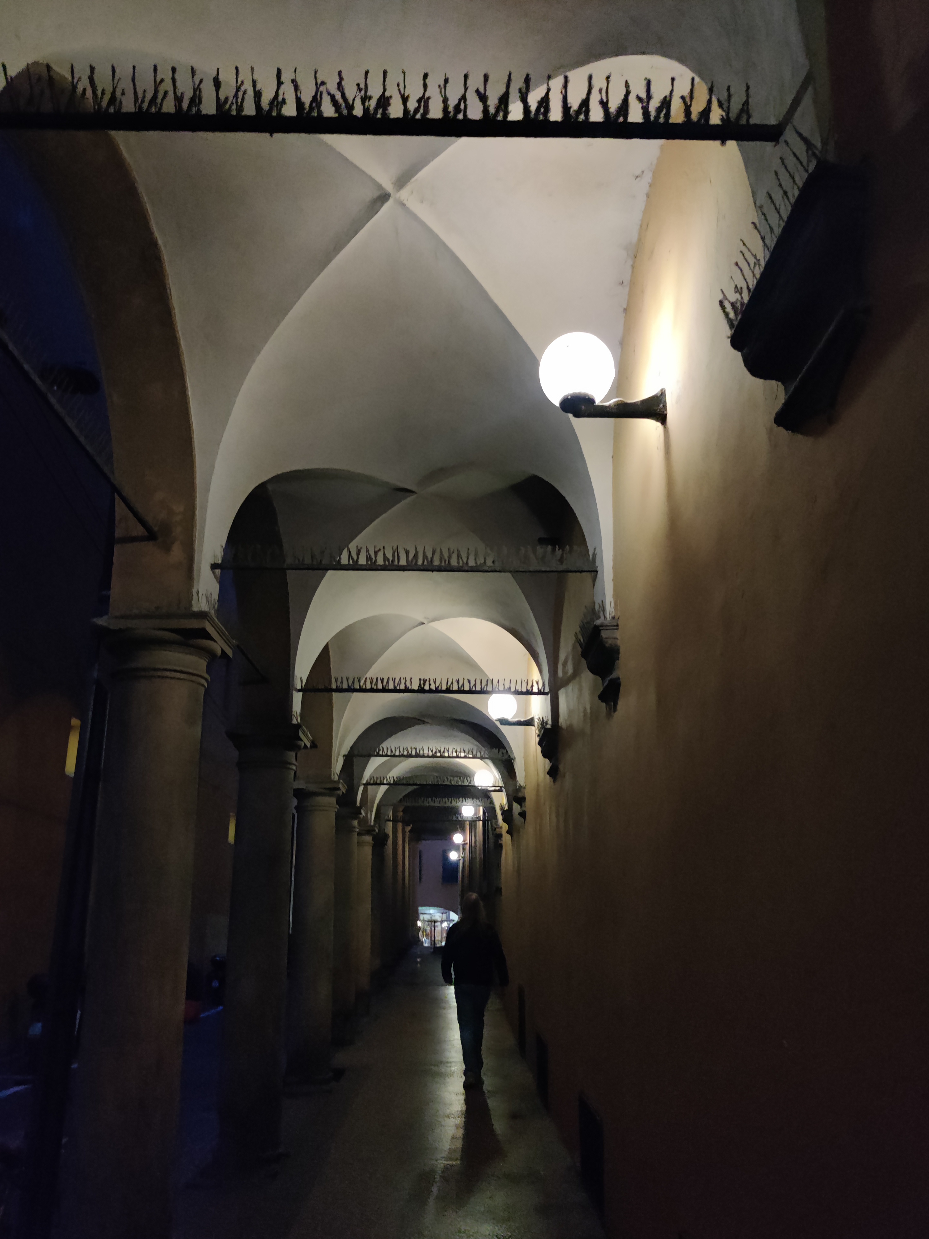 Dark atmospheric portico corridor with medieval groin-vaulted ceiling and globe wall lamps